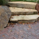 Random flat rock staircase leads to paver patio